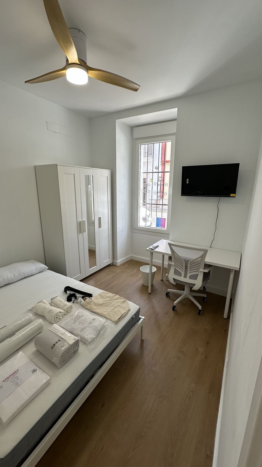 Habitación con armario, escritorio junto a la ventana y televisor