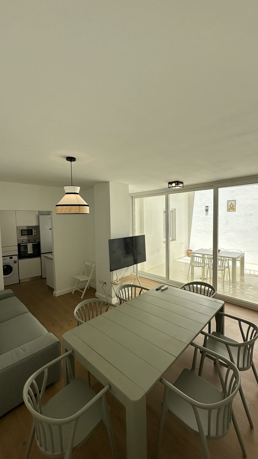 Salón comedor con mesa, sofá y televisor, con puerta corredera al patio